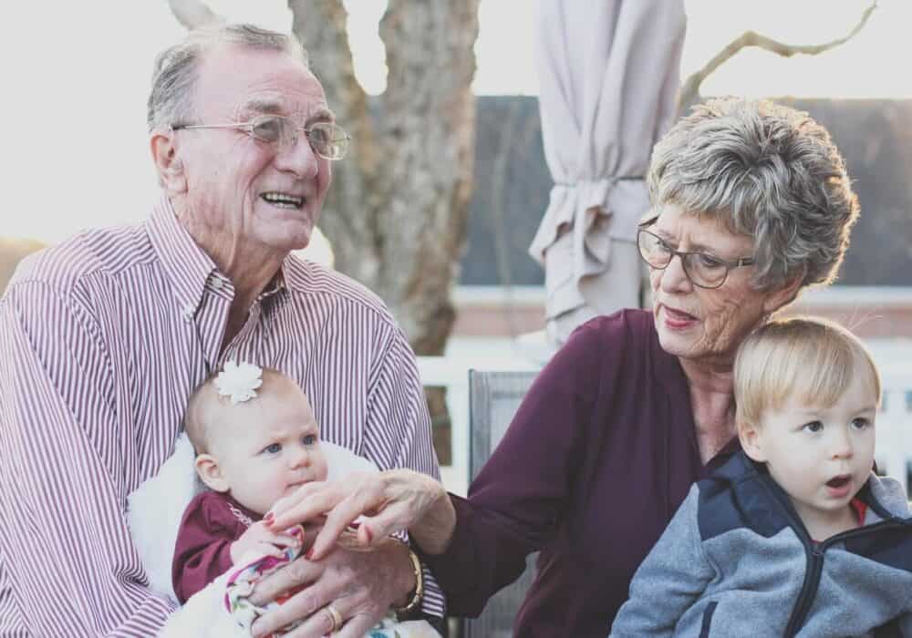 grandmother and a grandfather holding child on their lap